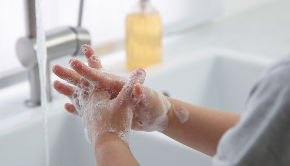 child's hands being washed under a faucet