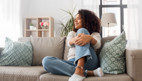 people-race-ethnicity-and-portrait-concept-happy-african-american-young-woman-sitting-on-sofa-at-home-600x344